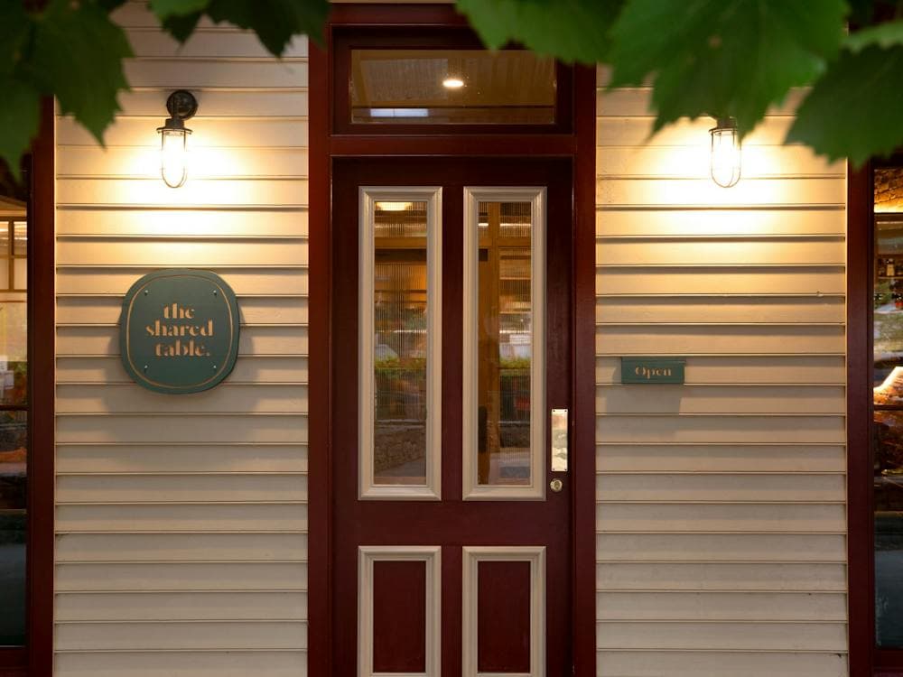 Front door of The Shared Table looking through grape vine leaves