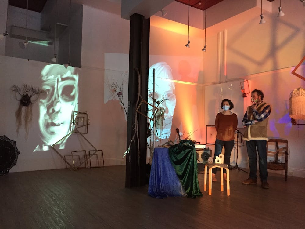 Two performers stanging in the space with digital projections on the wall.