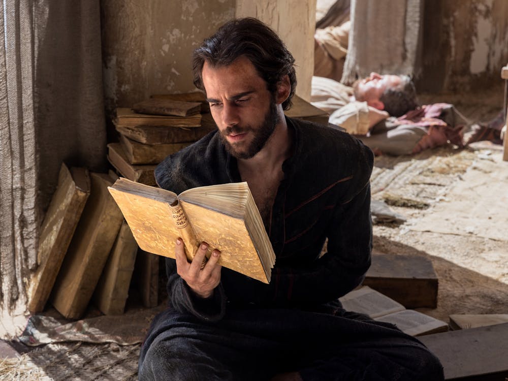 Man sits on ground reading book