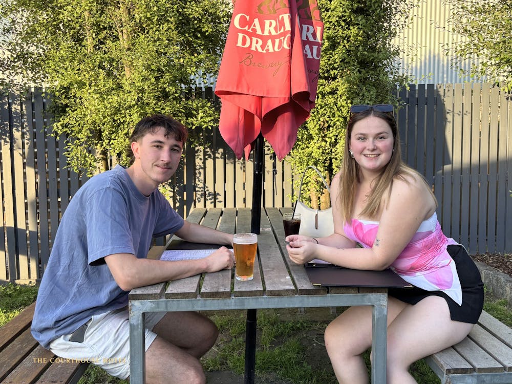 wo guests sitting at an outdoor table with drinks, relaxing in the Courthouse Hotel beer garden.