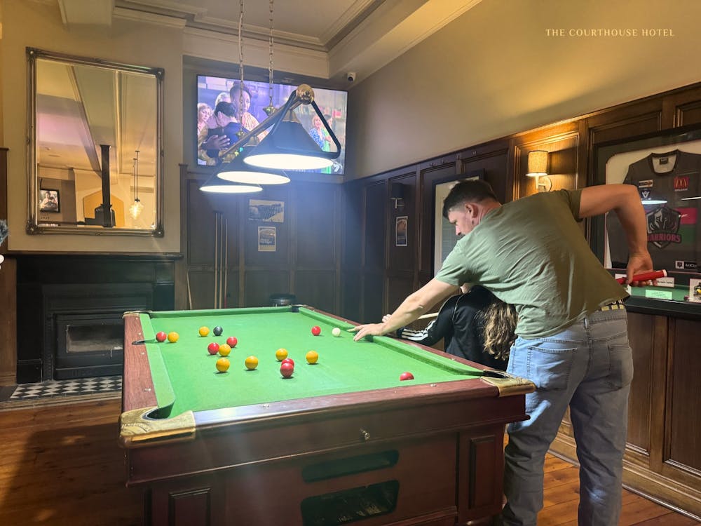 Two people playing pool on a billiards table inside the Courthouse Hotel bar.