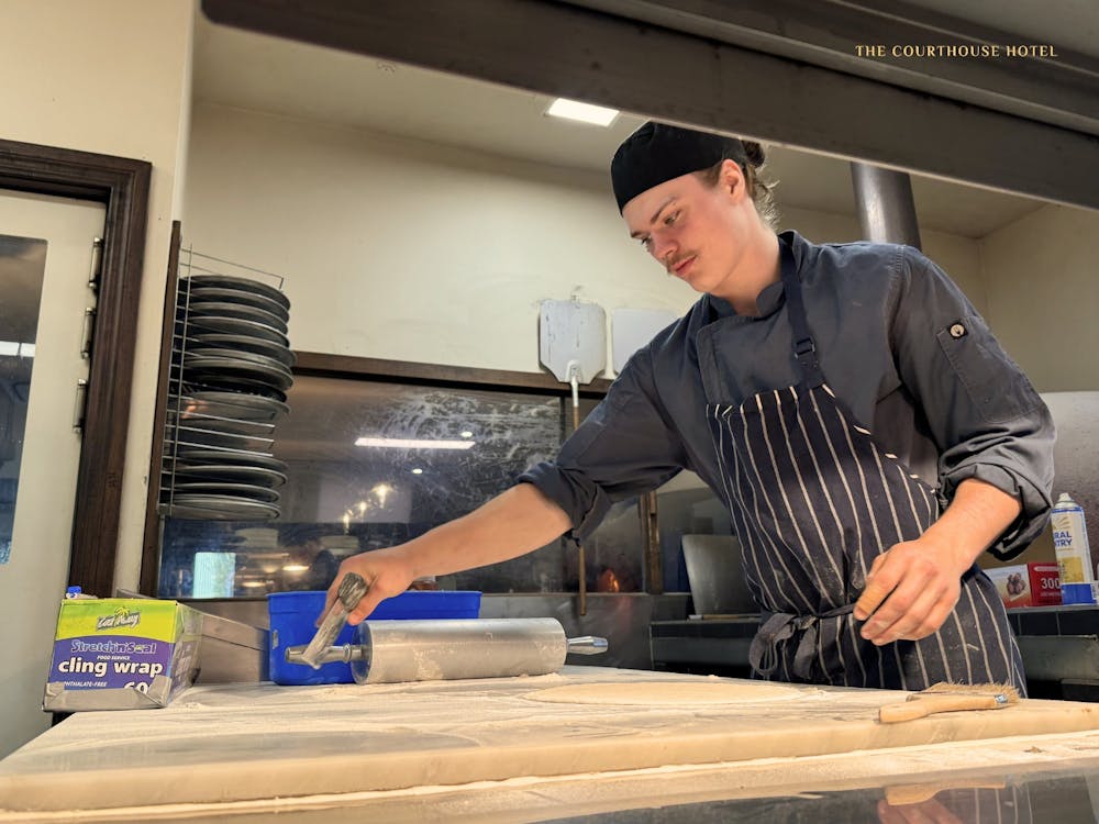 A chef working in the Courthouse Hotel kitchen preparing food on a wooden bench.