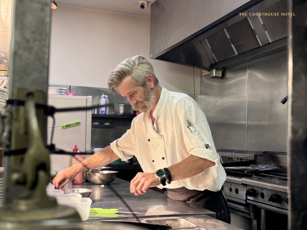 A chef carefully plating food in the professional kitchen at the Courthouse Hotel.