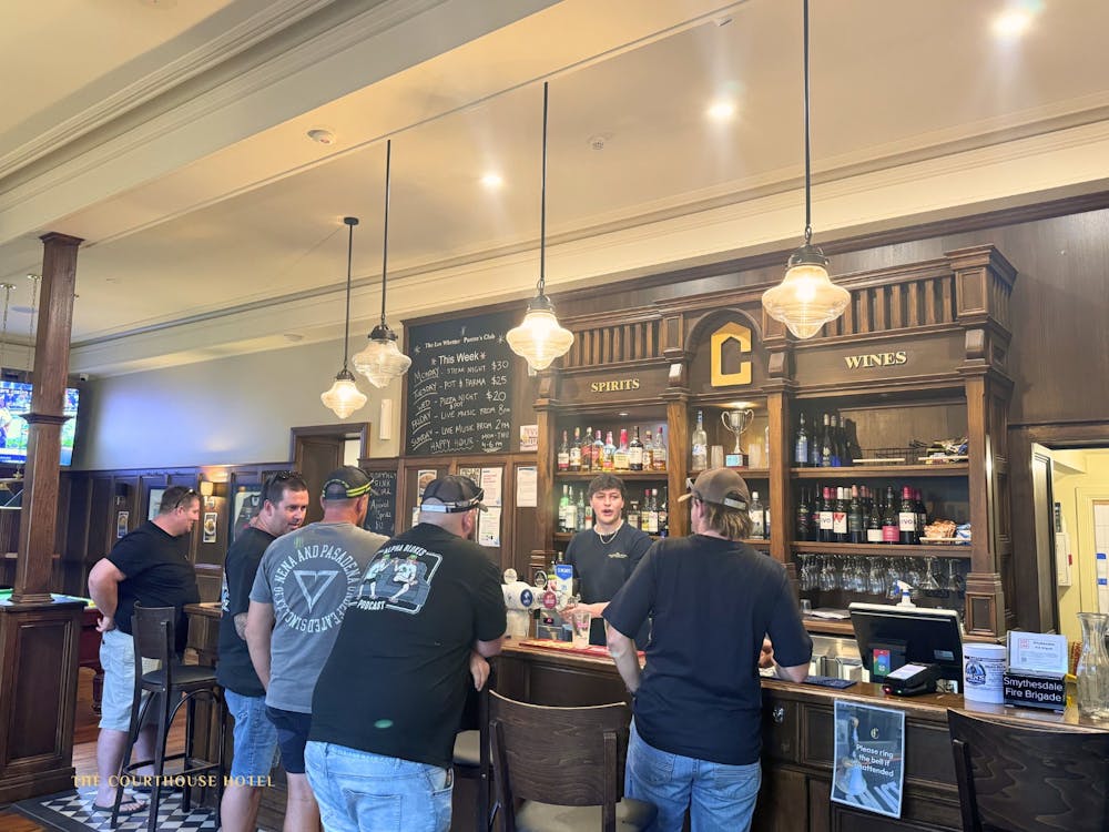 Patrons standing at the bar ordering drinks inside the Courthouse Hotel.