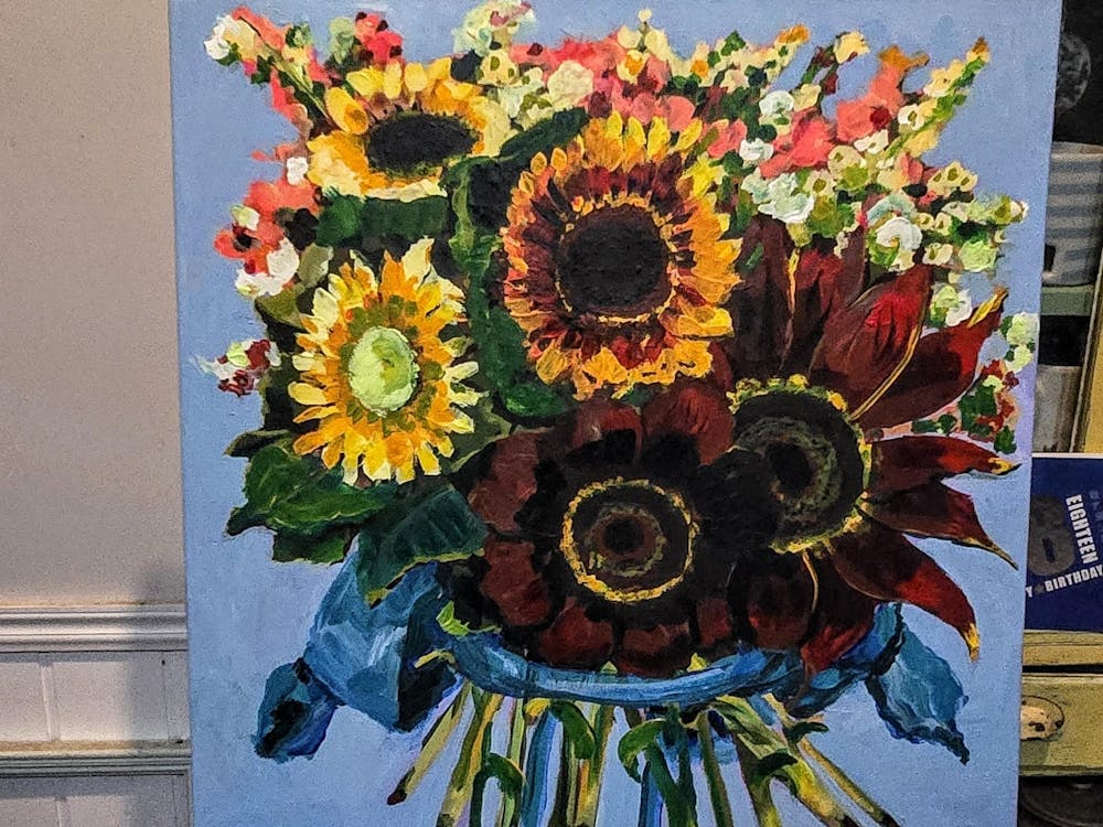 Clear vase with colourful sunflowers and other bright blooms