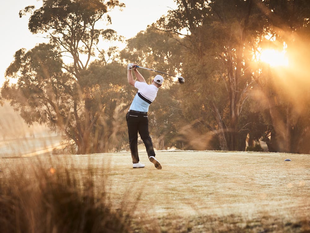 Man mid-swing on golf course