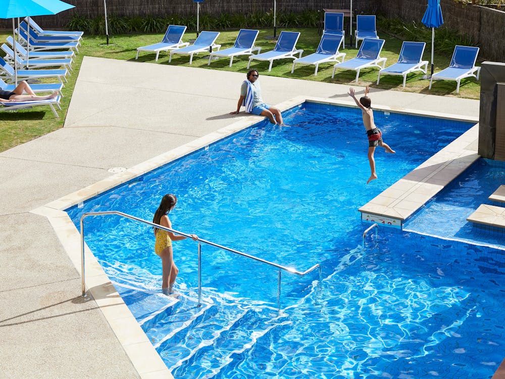 Family swimming and lounging by pool