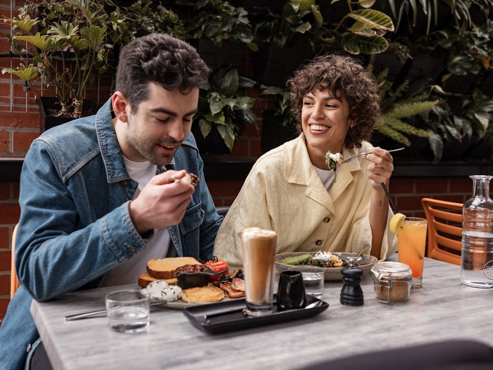Two guests enjoying brunch and coffee in the courtyard at Webster's MArket and Cafe.