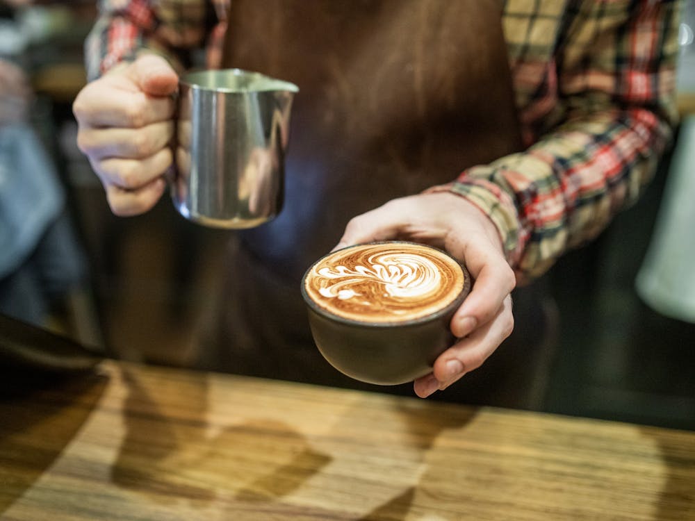 Barista pouring lattee art into a cup of specialty coffee at Webster's Market and Cafe.
