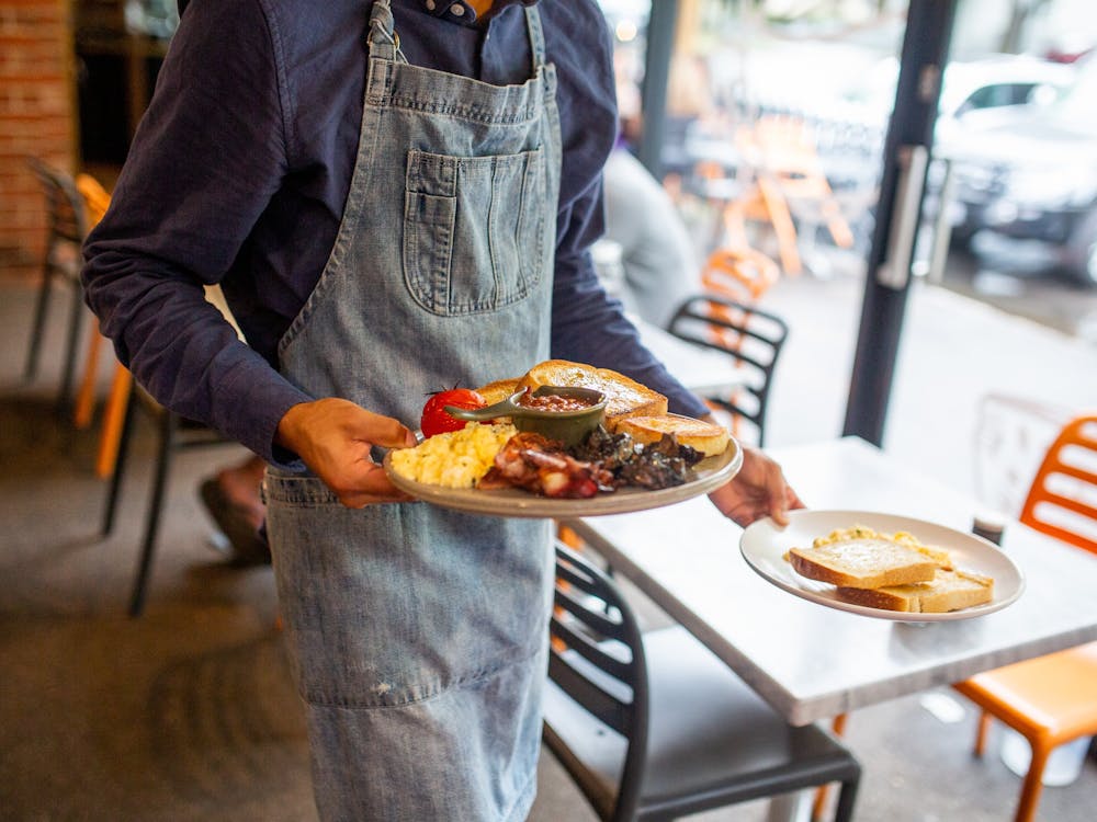 Staff member serving freshly prepared brunch dishes at Webster's Market and Cafe.