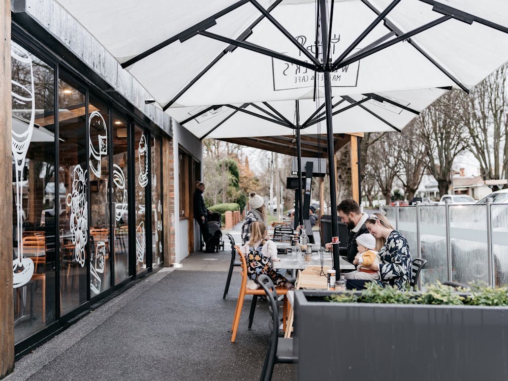 Outdoor seating at Webster's Market and Cafe on tree lined Webster Street.