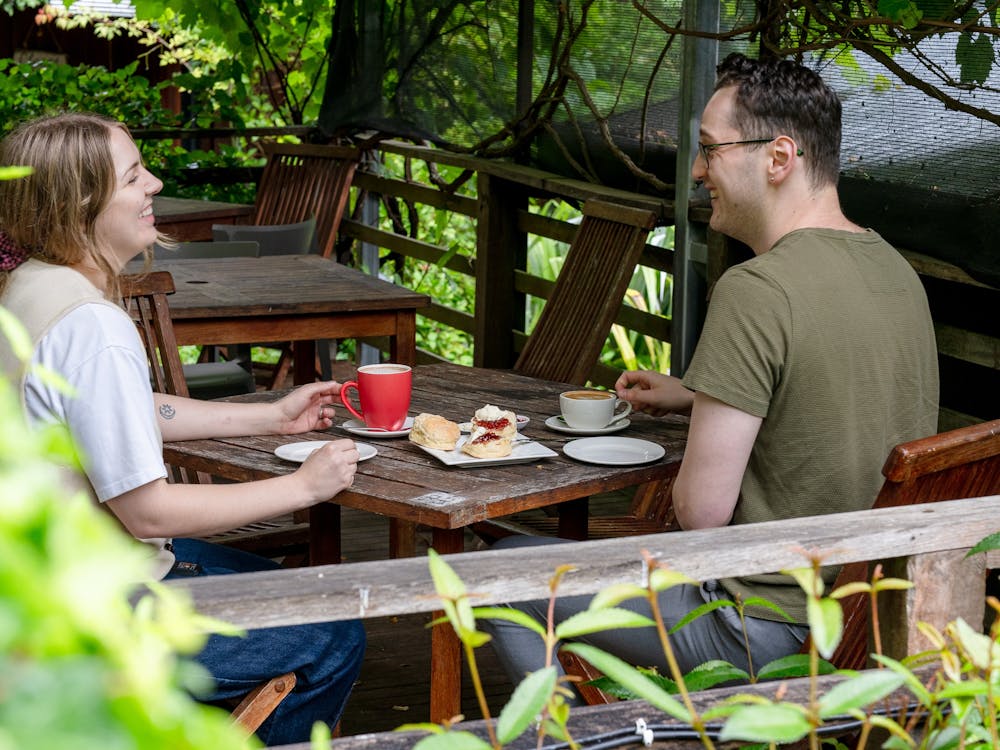 Couple sitting outdoors drinking coffee and eating scones
