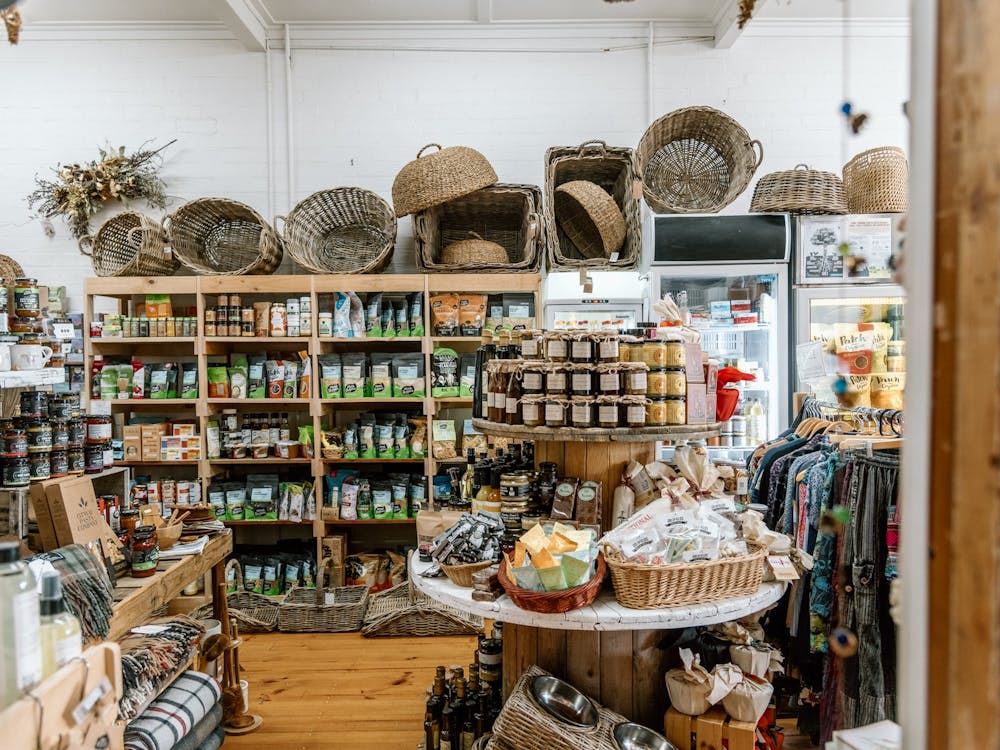 Shelves full of organic groceries, local preserves and cane baskets on top of the shelf.