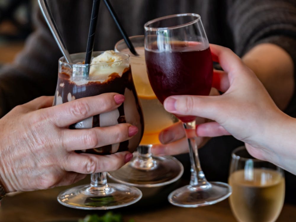 Guests clinking glasses over brunch with cocktails, coffee and sparkling wine.