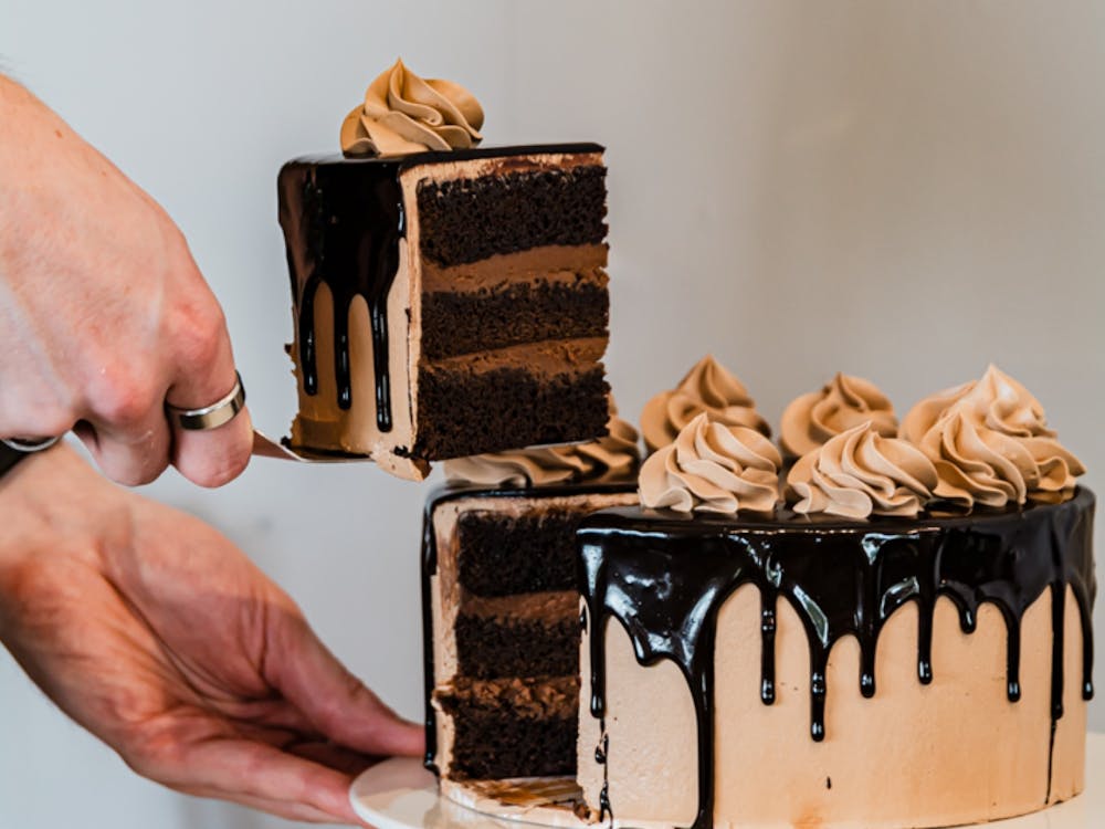 Slice of chocolate cake lifted from a layered cake with chocolate ganache