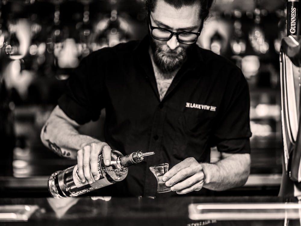 Bartender preparing a drink behind the bar at The Lake View Hotel.