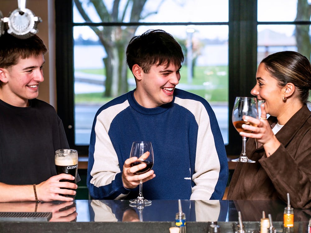 Three friends laughing together over drinks inside The Lake View Hotel.