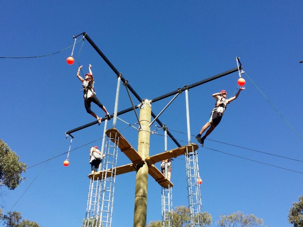 Four people at the top of a Leap of Faith activity. Two are jumping.