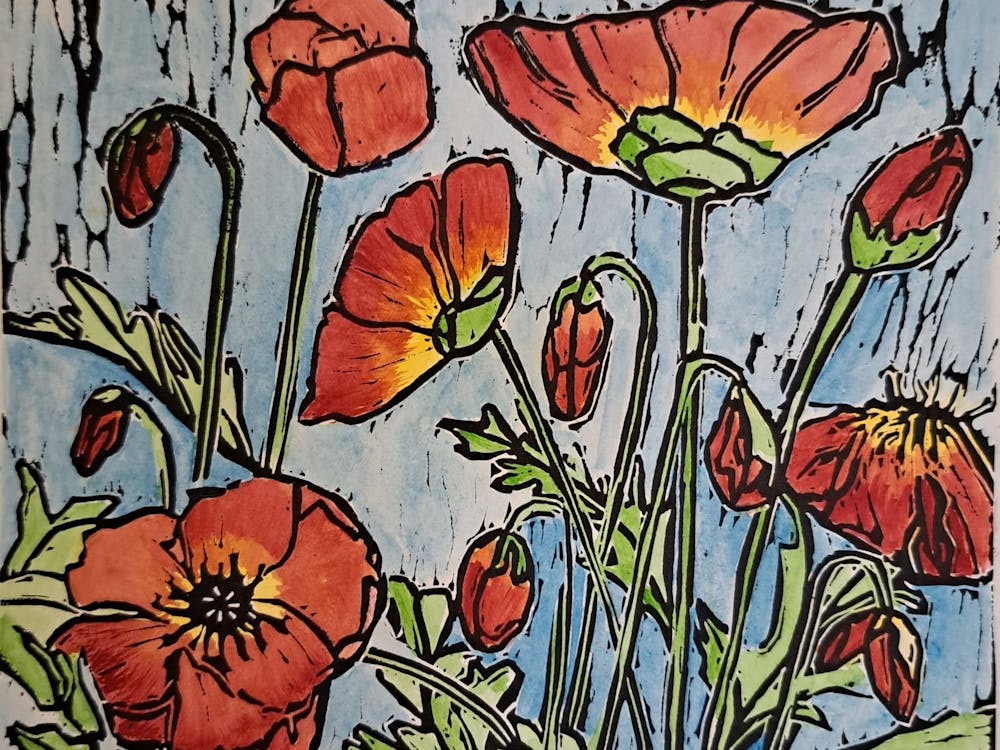 Lino print in black ink with colourful red poppies in a blue  background