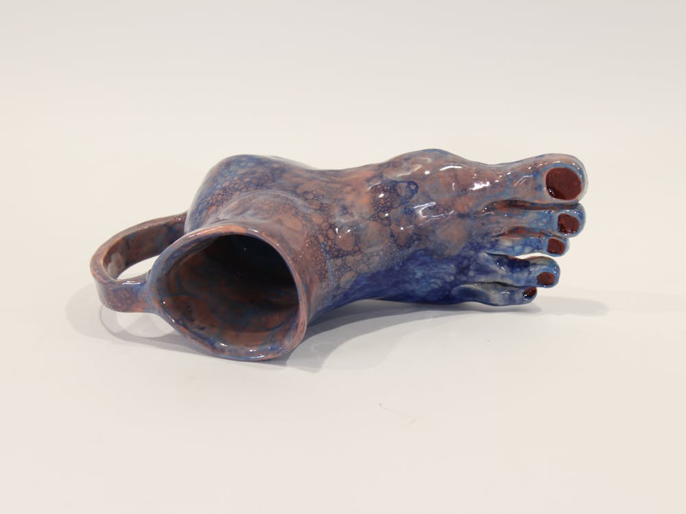Pottery of a mug that features a human foot as the base of the mug.