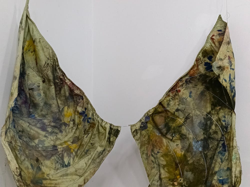 Dyed textile placed over a wire frame hanging from the wall.