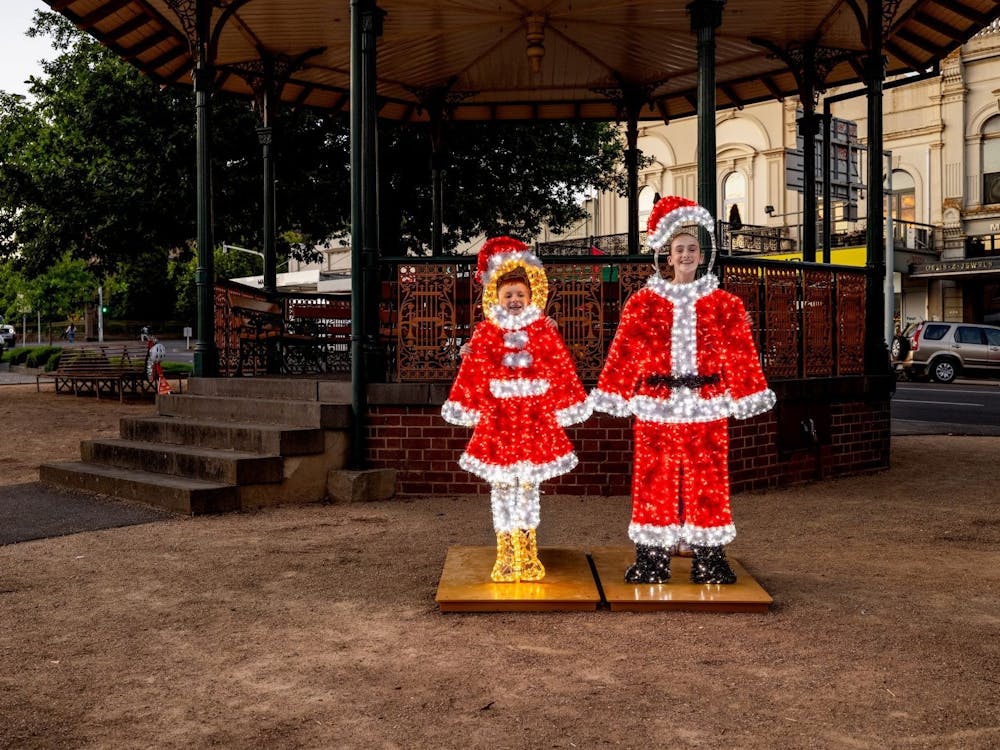 Two children put their faces into the holes to become Santa and Mrs Clause