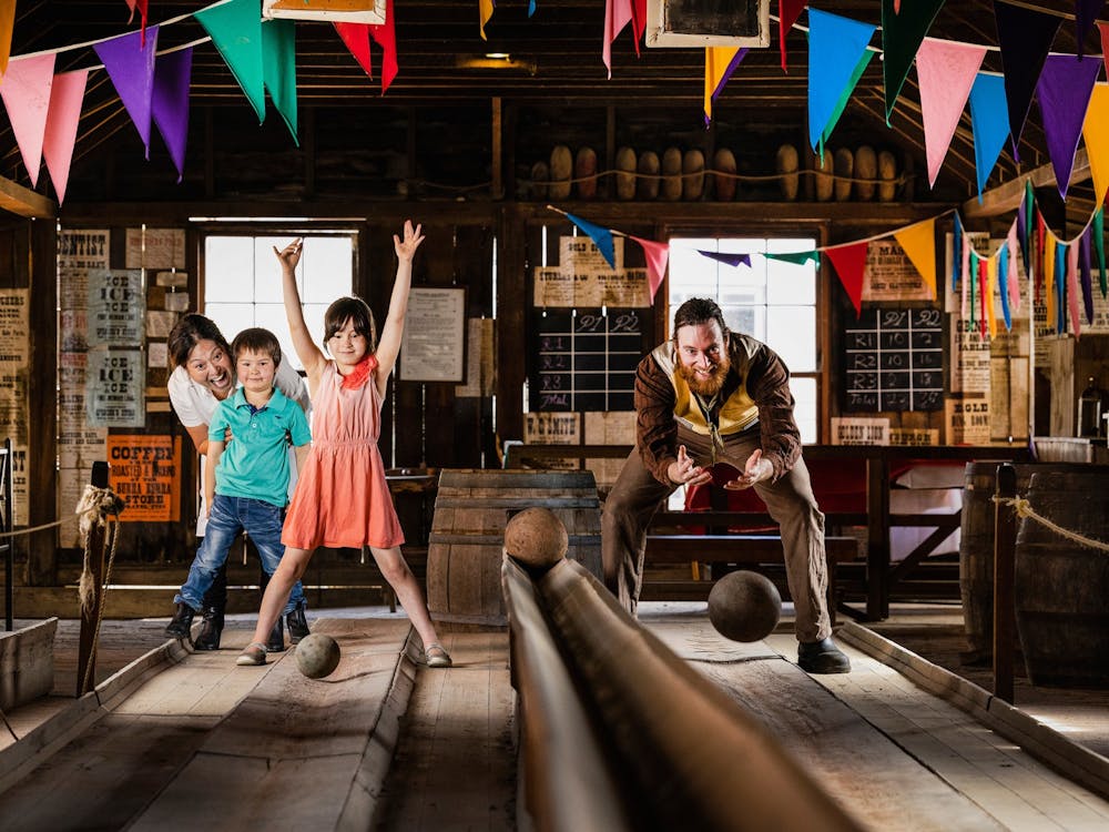 Boy and girl bowling with man in 19th century costume