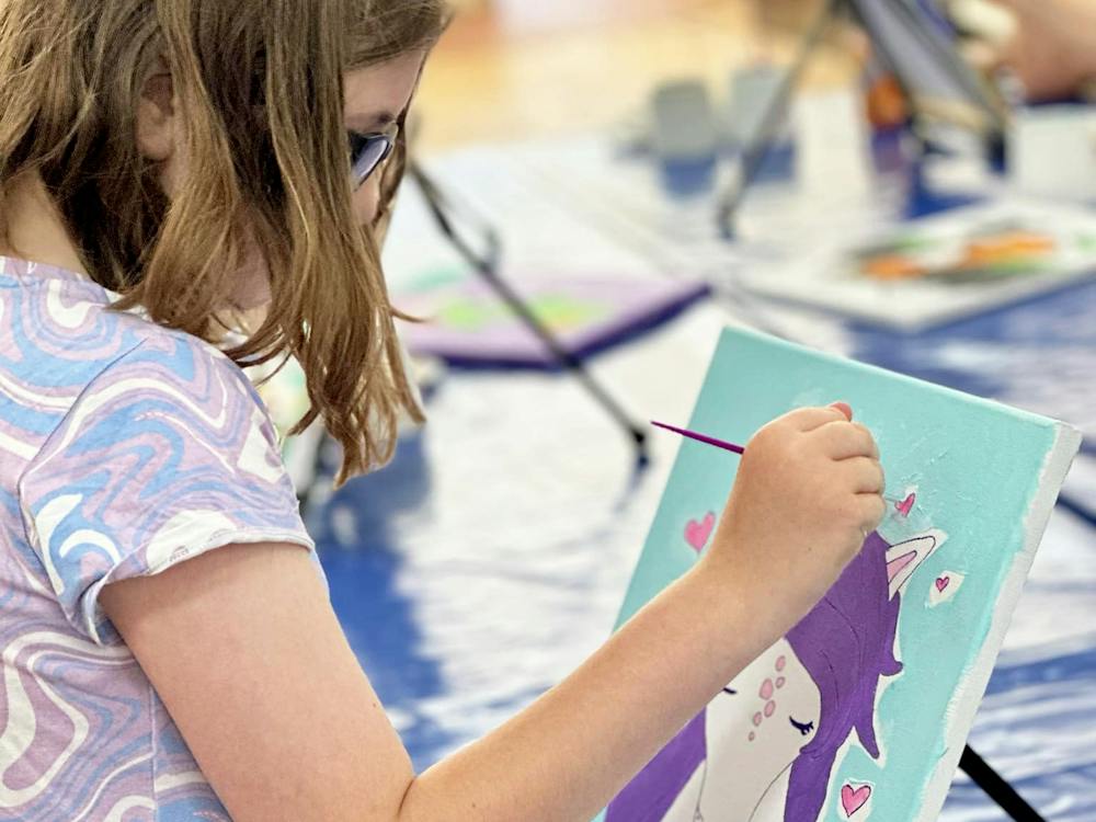 Child painting a unicorn canvas