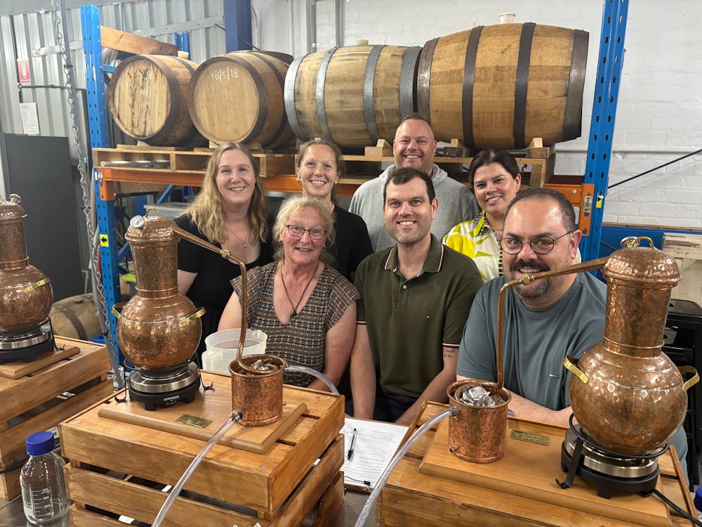 Seven adults in a group behind gin stills