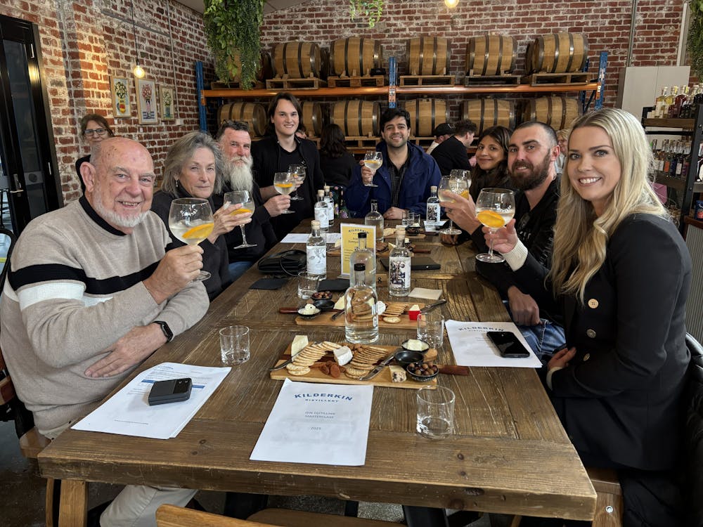Group of eight people sitting having gin and tonics with cheese