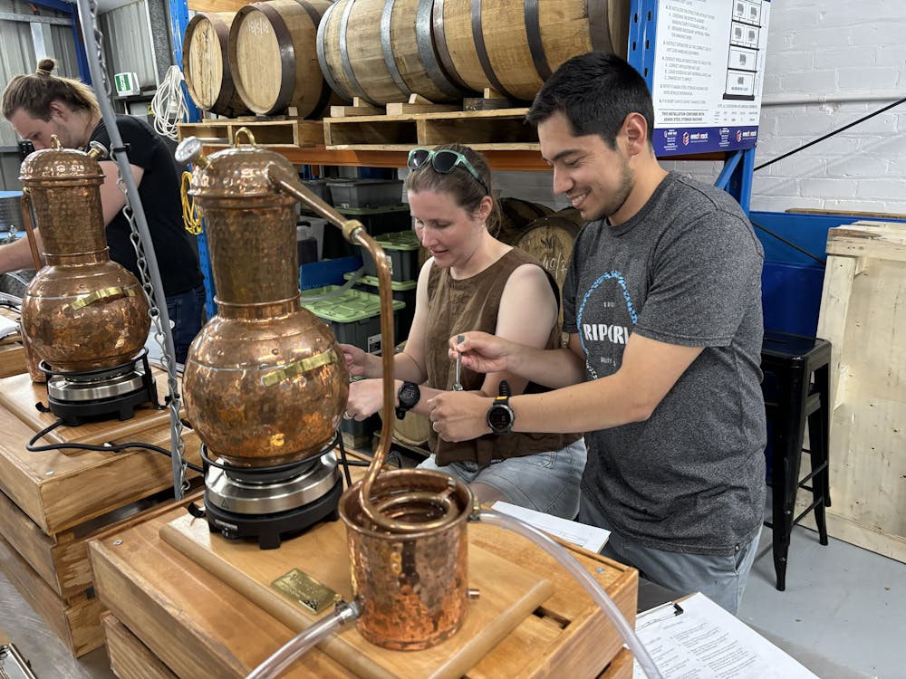 Two adults working with small still in bench