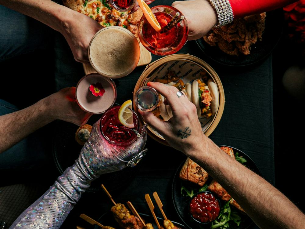 Overhead view of friends enjoying cocktails, bao buns, pizza and share plates at Piano Bar Ballarat.
