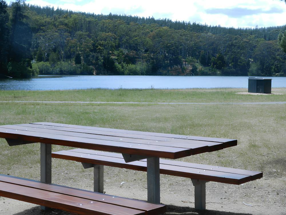 Standing behind a picnic table looking out and over the the nearby St Georges Lake with blue skies