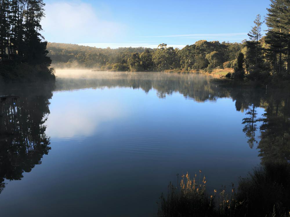 Standing on the bank of St Georges Lake looking out to the reflective water with blue skies & trees