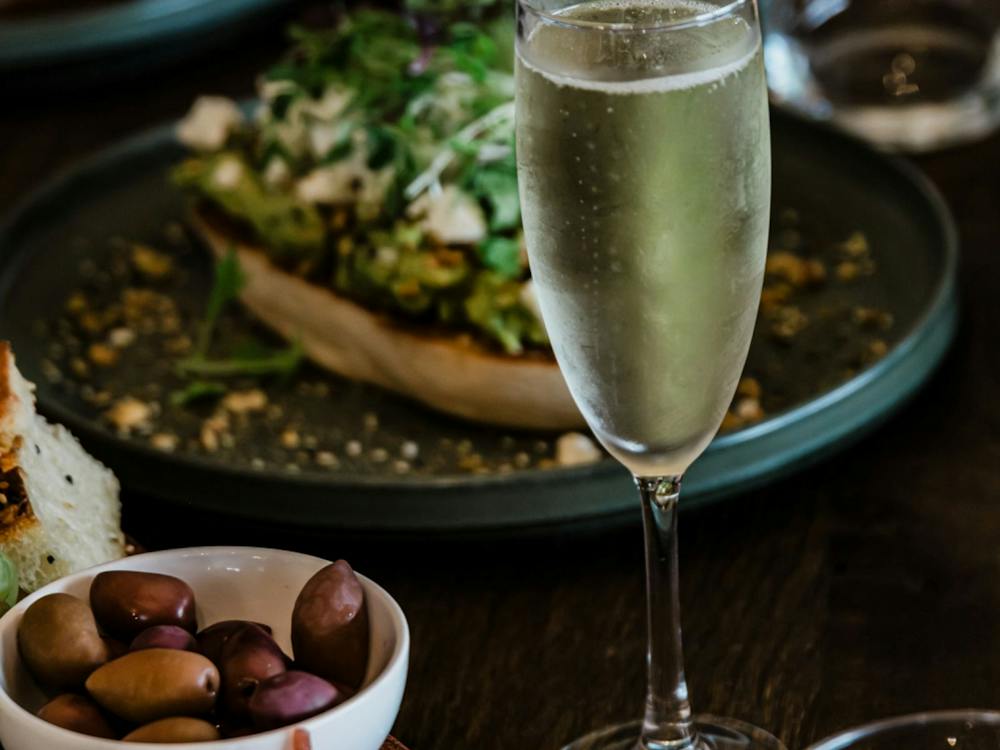 A glass of Champagne sits surrounded by plates of food