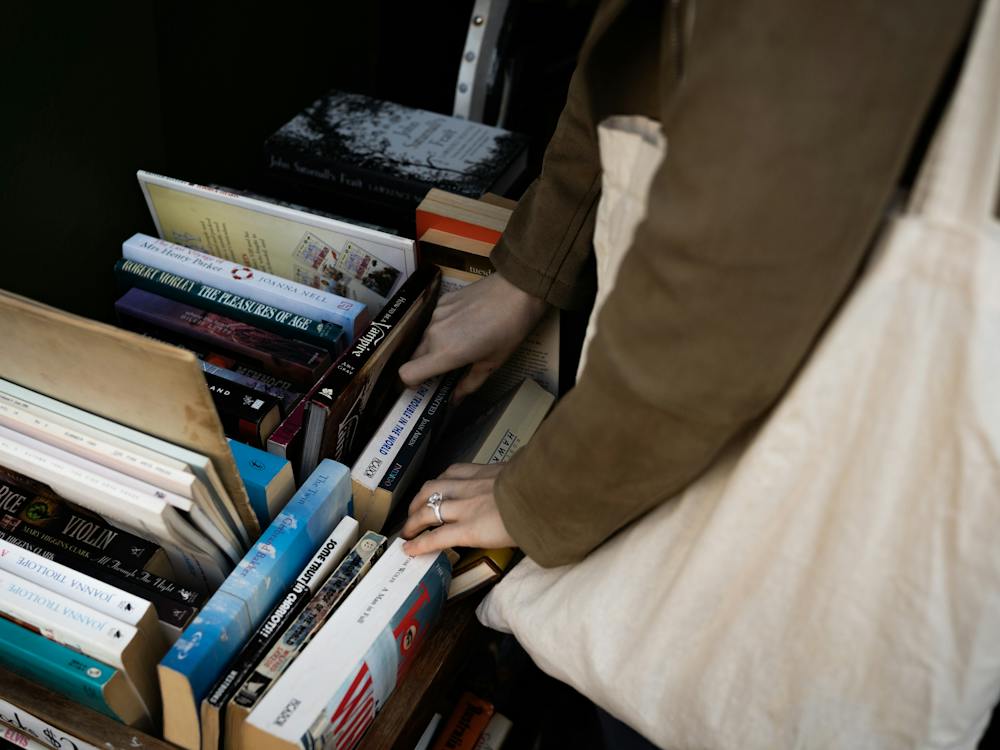A person holding a tote bag peruses a book stall.