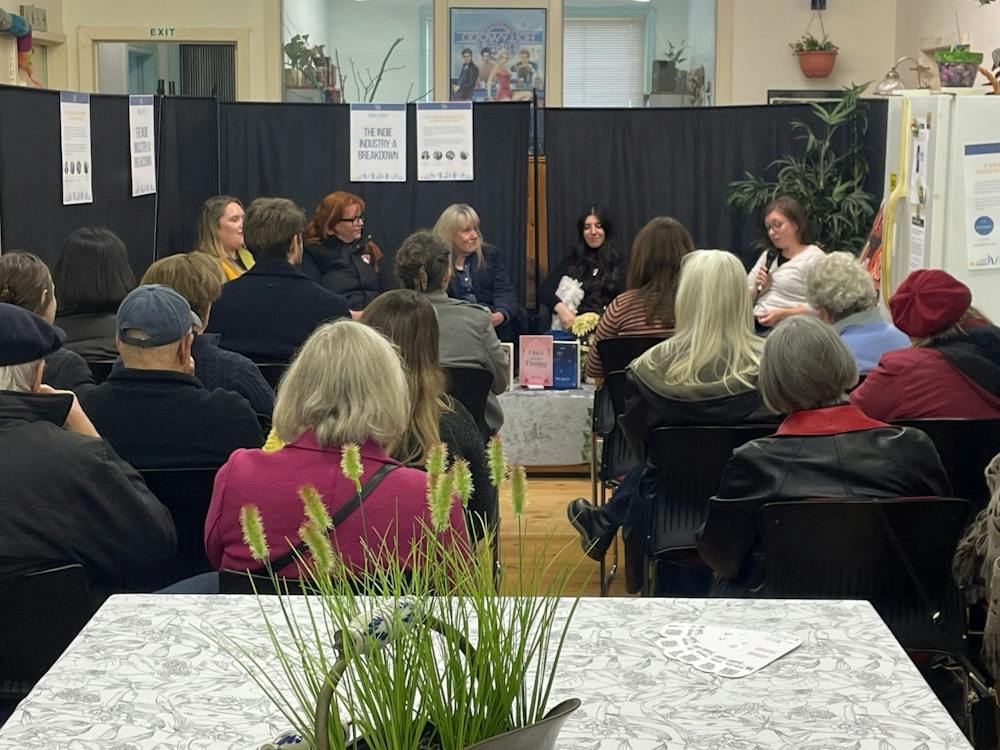 Background features five women talking about publishing industry. Back of audience in foreground,