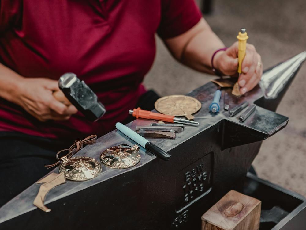 Close up of hands working with metal on anvil