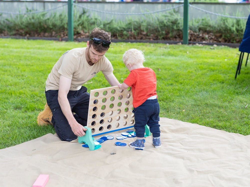 A toddler plays connect 4 with his father.