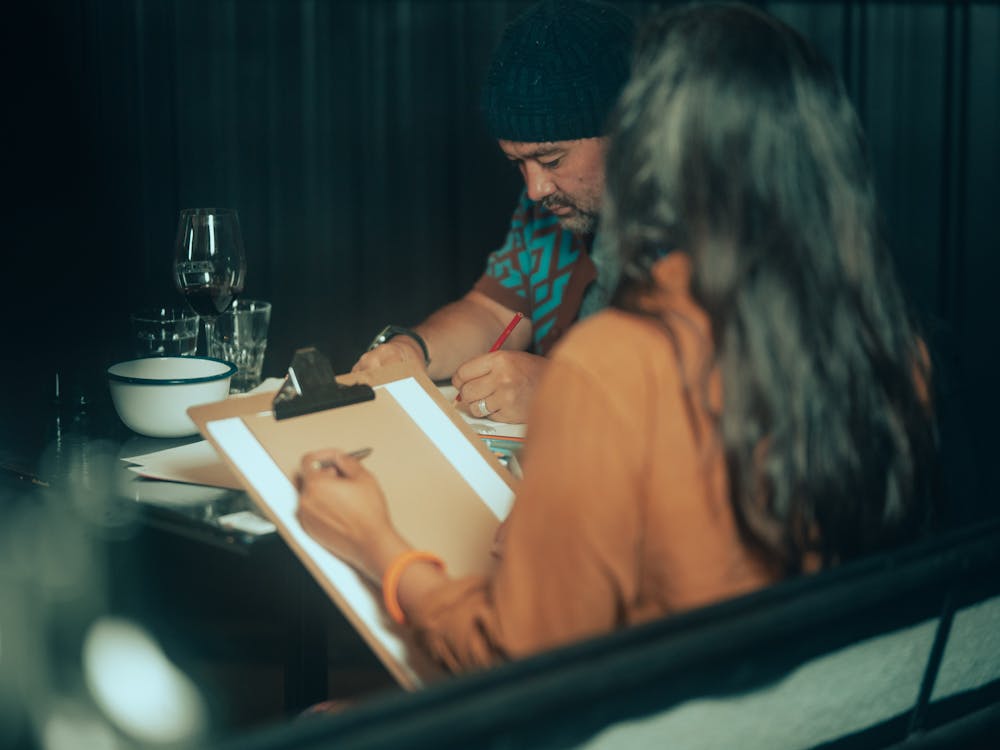 Two people drawing with wine on table